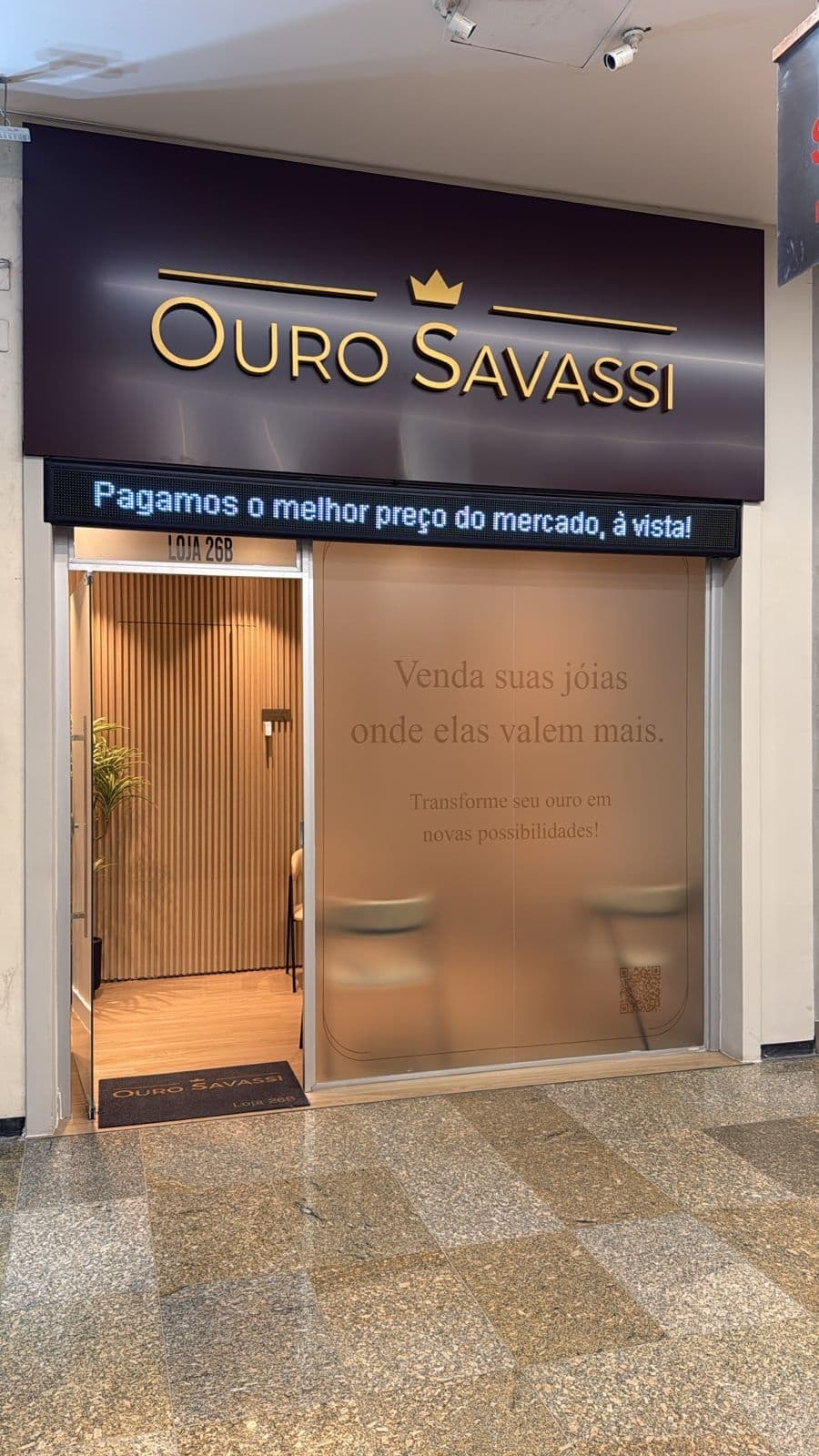 Fachada da loja Ouro Savassi na galeria Quinta Avenida, Savassi — Belo Horizonte. Testeira marrom escuro com logo dourado e coroa.